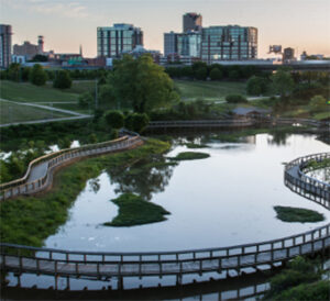 Curving boardwalk over wetlands toward city skyline