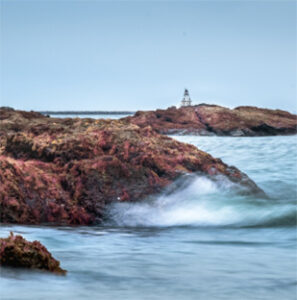 Rocky shoreline with distant lighthouse and waves