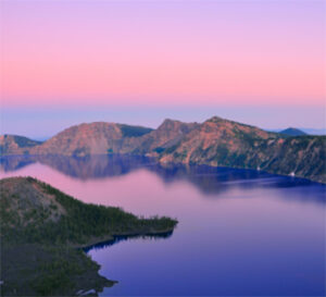 Calm crater lake at sunrise with pink sky