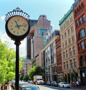 Ornate street clock beside downtown city buildings
