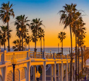 Sunset palm-lined beachfront pier with golden sky