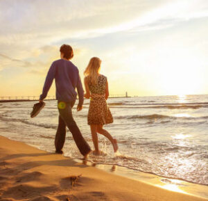 Couple walking barefoot on sunset beach