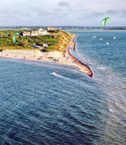 Aerial view of beach headland with kiteboarders