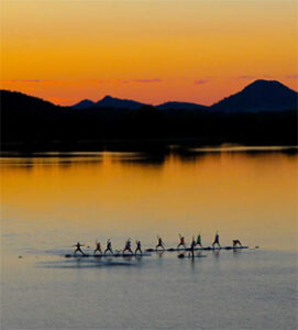 Crew team rowing on golden sunset lake