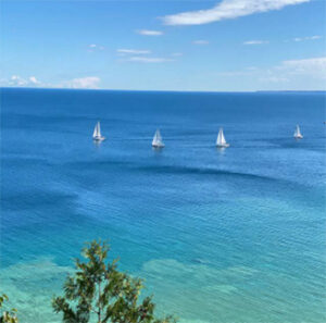 Four sailboats sailing across turquoise blue sea