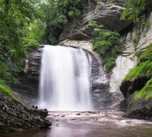 Wide waterfall flowing through forested gorge