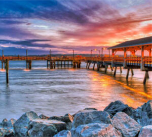 Sunset pier stretching over rocky shoreline
